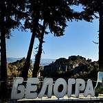Vista panoramica delle formazioni rocciose di Belogradchik in Bulgaria, con la scritta in cirillico in primo piano tra gli alberi