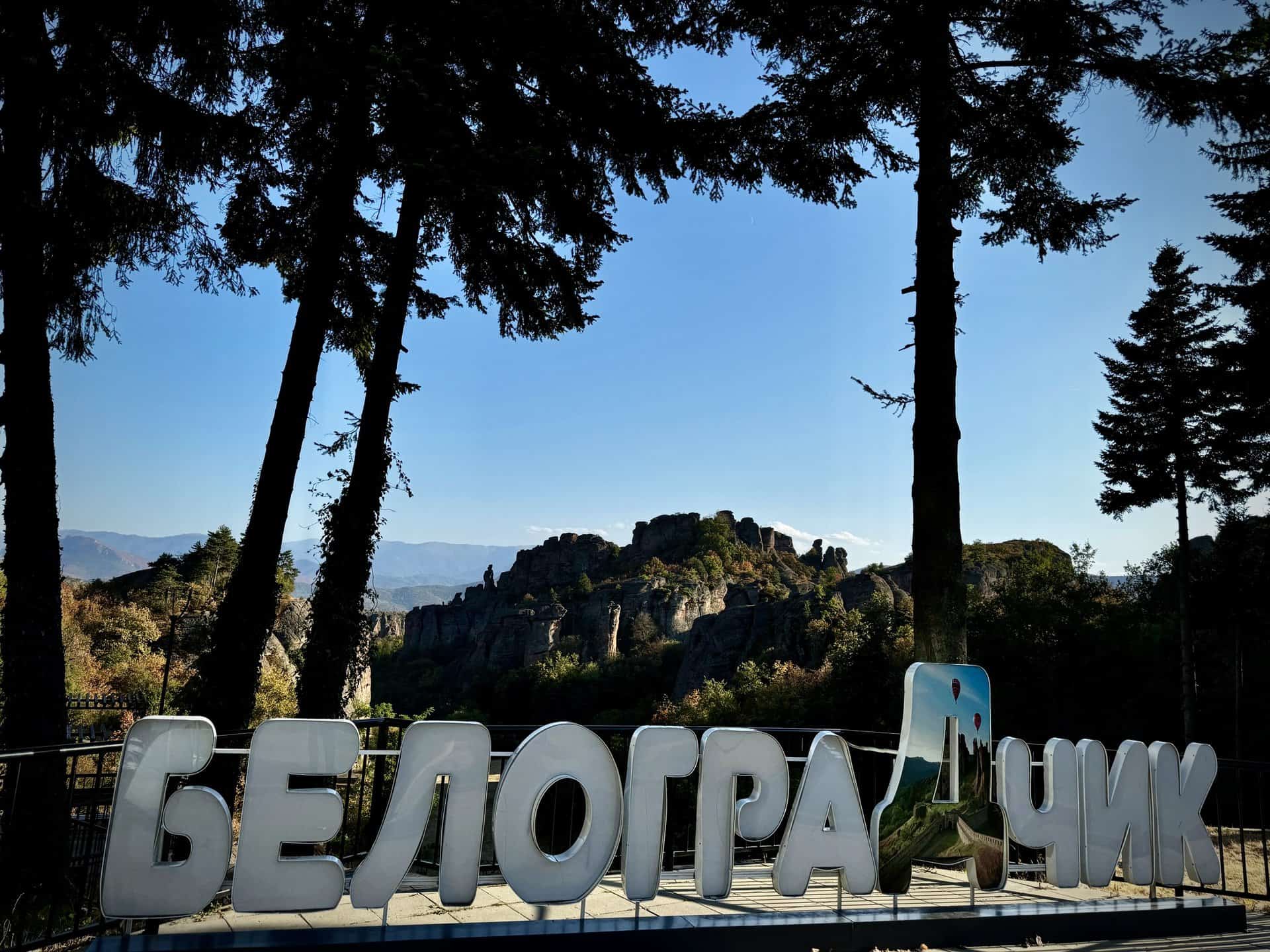 Vista panoramica delle formazioni rocciose di Belogradchik in Bulgaria, con la scritta in cirillico in primo piano tra gli alberi