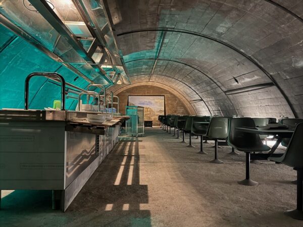 Interno della mensa del bunker antiatomico con tavoli, sedie e banconi originali in stile anni '60.