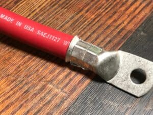 Dettaglio di cavo di potenza rosso con capocorda ad anello crimpato su terminale metallico.