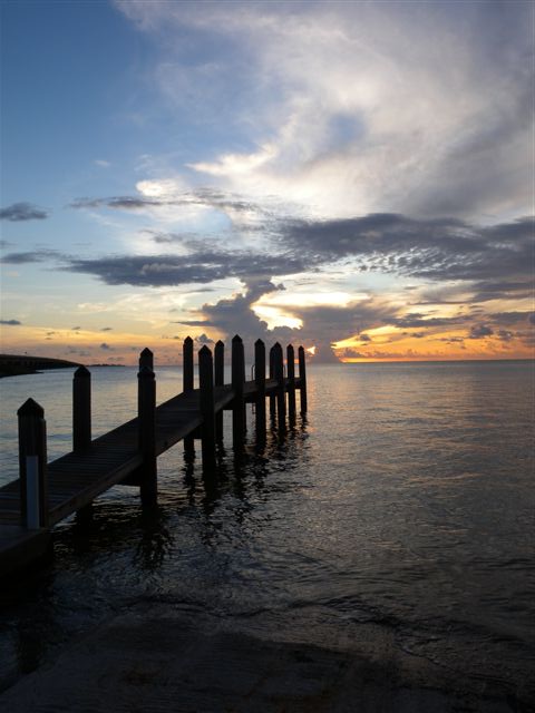Traghetto di legno sul lago durante il tramonto con cielo nuvoloso.