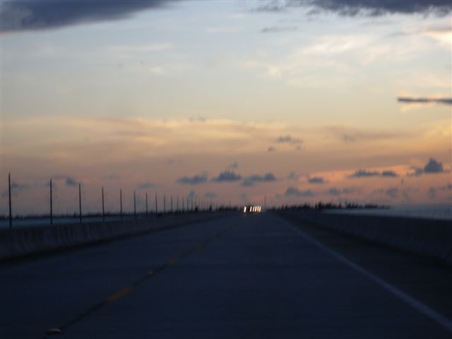 Strada deserta al tramonto con cielo colorato e nuvole sparse.