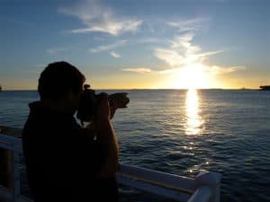 Fotografo che scatta foto al tramonto sul mare con una vista panoramica.
