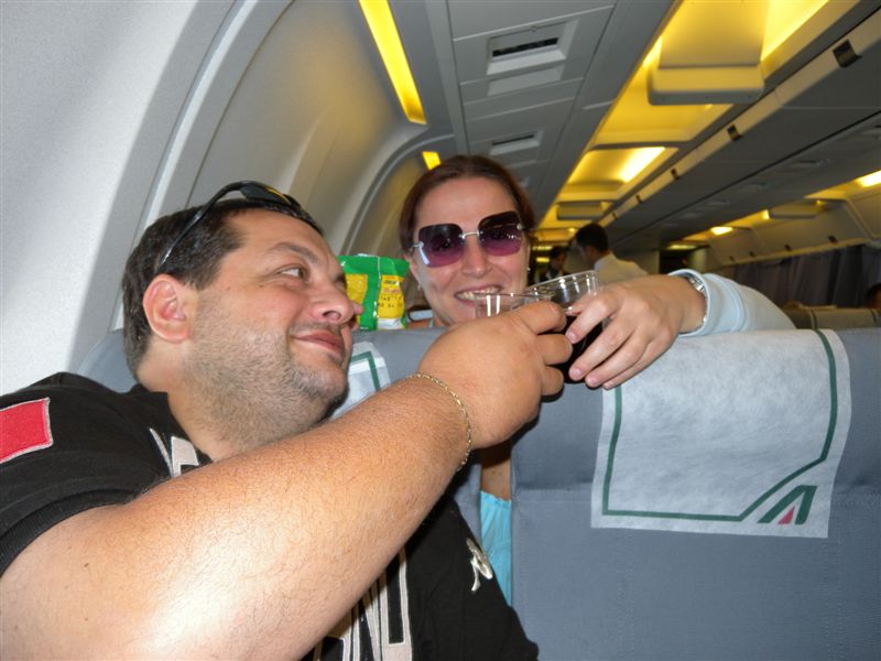 Viaggio in aereo con amici, drink e atmosfera rilassata.