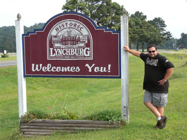 Segnale storico di Lynchburg con benvenuto, vicino a un parco verde.