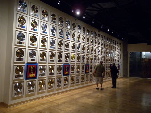 Muro con numerosi premi e riconoscimenti musicali in una sala espositiva.
