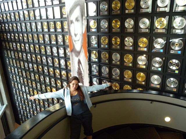 Donna davanti a parete di dischi in vinile e foto storica.