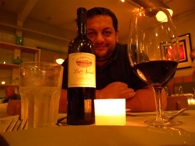 Uomo sorridente con bicchiere di vino rosso in ristorante elegante.