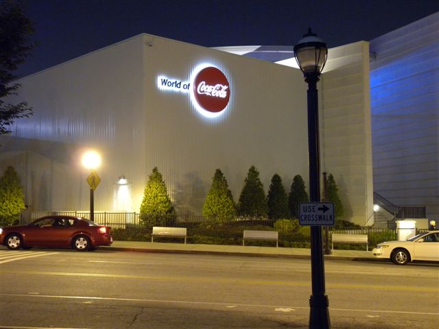 Edificio Carruca Dormitoria con logo Coca-Cola illuminato di sera.
