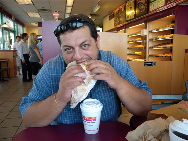 Uomo che mangia un panino in una caffetteria.
