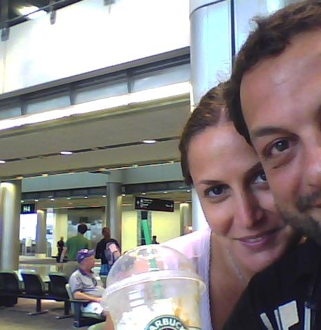 Due persone sorridenti in aeroporto con caffè Starbucks, viaggio e relax.