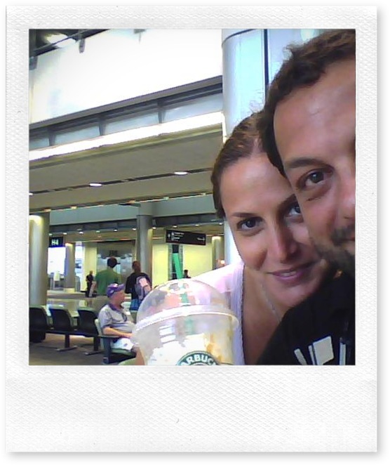 Coppia sorridente con bevanda Starbucks in aeroporto.