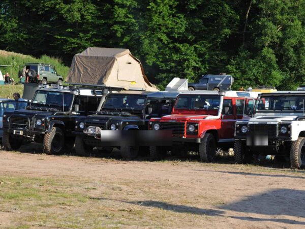 Fila di Land Rover Defender in Camp Area con tenda da tetto sullo sfondo