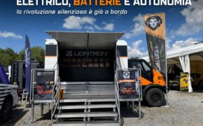 Il truck-palco dello stand Liontron ad Abenteuer & Allrad con batterie LiFePO4 esposte, bandiere del brand e camion Tekne arancione