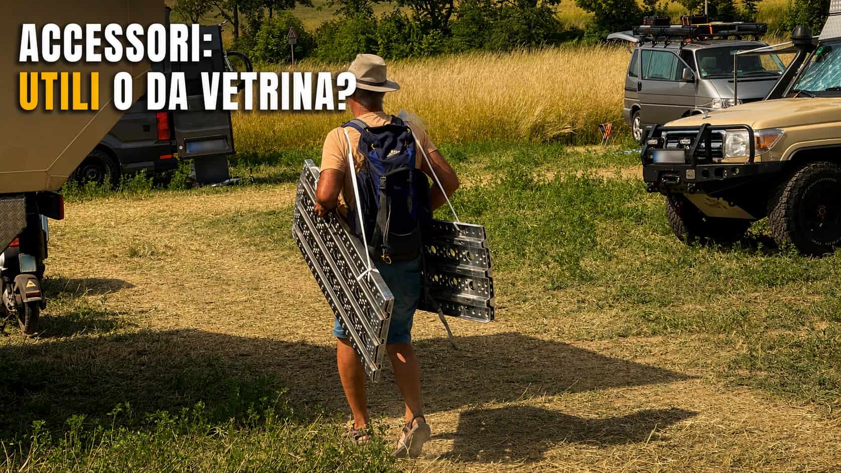 Visitatore di spalle trasporta due piastre da sabbia in alluminio appena acquistate verso il proprio mezzo, tra camper e fuoristrada