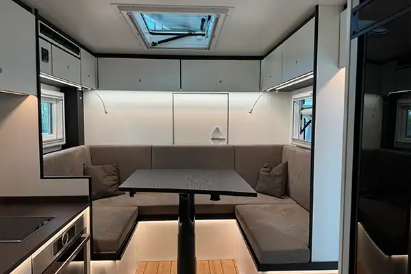 Zona giorno della Kerkamm EX 592: dinette a U, pensili chiari, oblò sul tetto