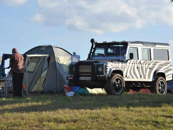Land Rover Defender con livrea zebrata e tenda a terra in Camp Area