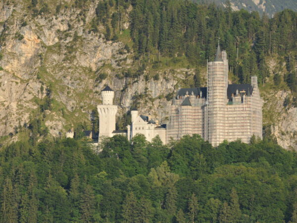 Il Castello di Neuschwanstein tra i boschi, ai piedi della parete rocciosa, nella luce della sera