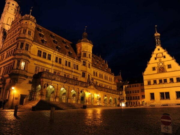 Il Rathaus illuminato di notte sulla Marktplatz deserta di Rothenburg ob der Tauber