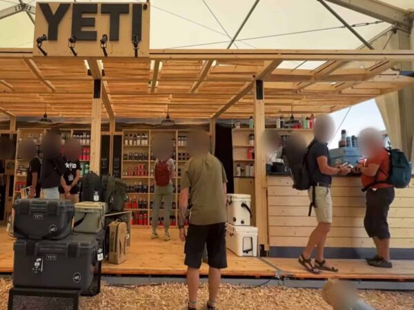 Lo stand YETI ad Abenteuer & Allrad 2026: scaffali in legno con borracce e bicchieri Rambler, frigo portatili in primo piano