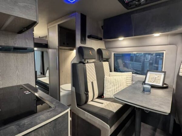 Interno del Robeta Apollo: dinette con tavolo, sedile trapuntato e blocco cucina