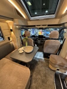 Dinette del Knaus SKY TI VW con il tavolo e, sopra la cabina, la finestra apribile in vero vetro