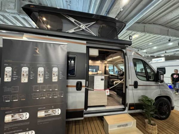 Robeta Apollo con il tetto a soffietto aperto allo stand Robeta del Salone del Camper 2026, porta laterale aperta e pannello delle piante