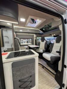 Interno dell&rsquo;Arca Mascotte 2027: cucina, dinette con i sedili girati e tetto vetrato sopra la cabina