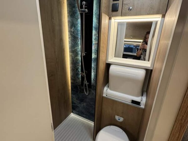 Bagno dell’Atlantis a interni chiari con doccia separata a parete scura, lavabo, specchio e wc