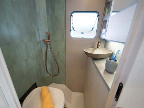 Il bagno del c.core con la parete effetto piastrelle verdi e la doccia