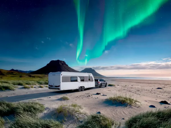 Immagine di catalogo Knaus Nordwind: la caravan al traino di un SUV su una spiaggia con l&rsquo;aurora boreale